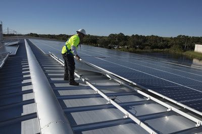 A man is working on a roof with solar panels.