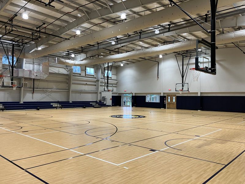 A large indoor basketball court with a wooden floor and a basketball hoop.