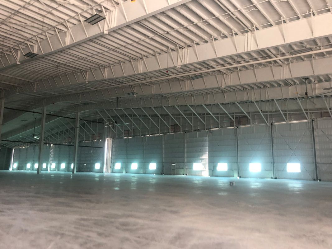 A large empty warehouse with a lot of windows and a ceiling.