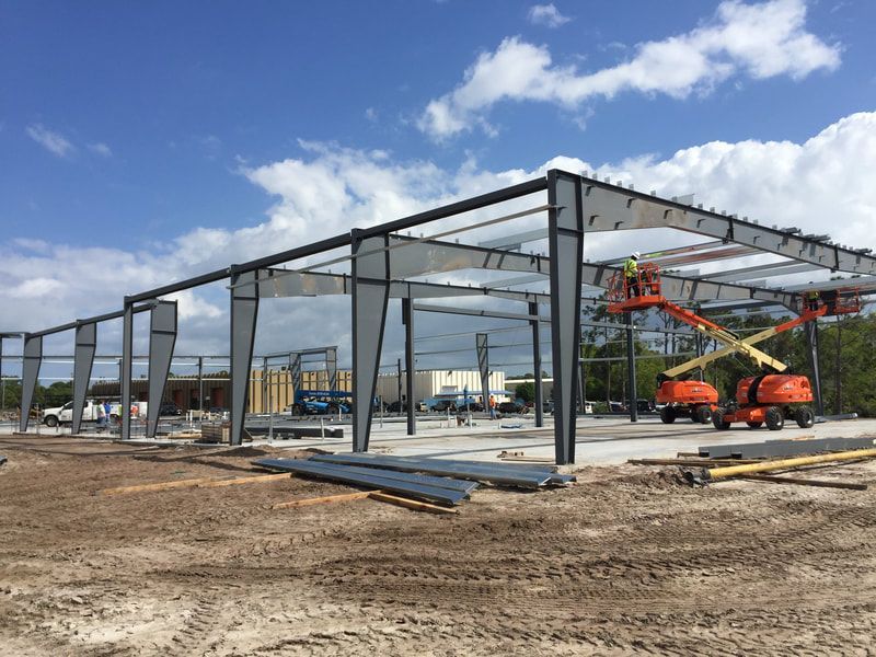 A large metal structure is being built in a dirt field.