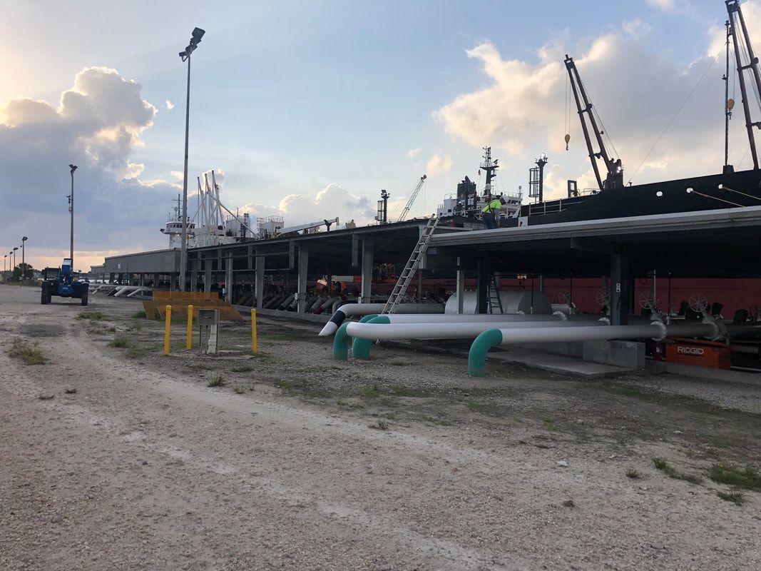 A construction site with a lot of pipes and cranes in the background.