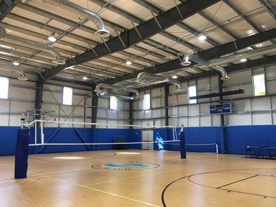 There is a volleyball net in the middle of the gym.