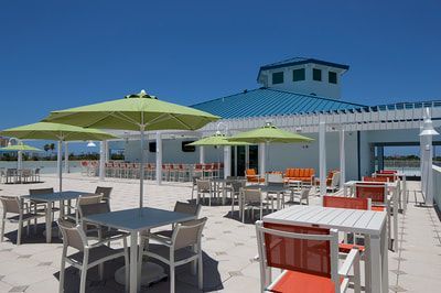 A patio with tables and chairs and umbrellas in front of a building.