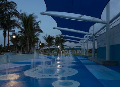 A fountain in a park with a blue floor and a blue umbrella.