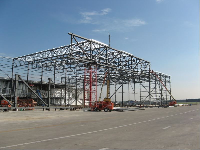 A large metal structure is being built on an airport runway.