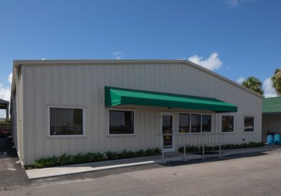 A white building with a green awning over the door.