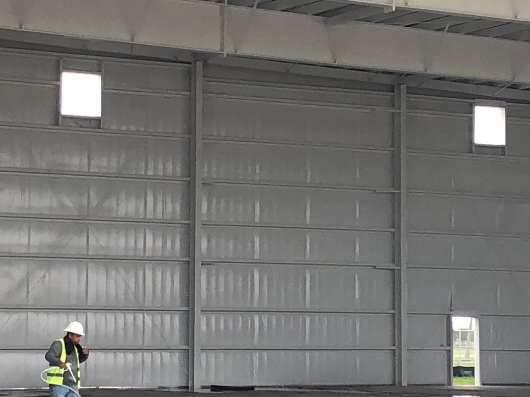 A man in a hard hat is standing in a large building.