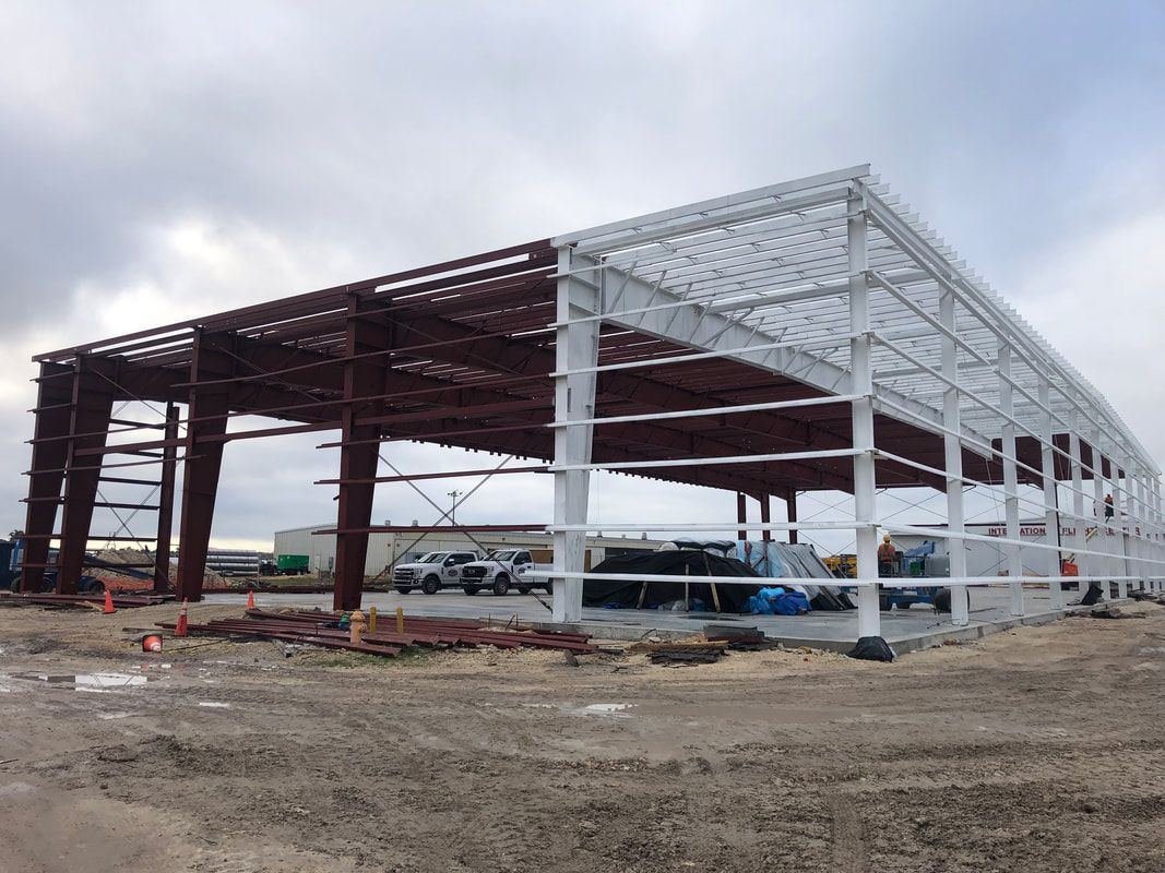 A large metal structure is being built in the middle of a dirt field.