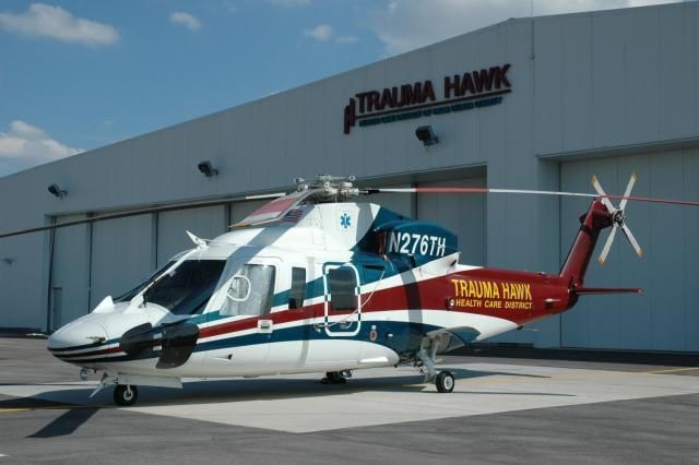 A helicopter is parked in front of a building that says trauma hawks