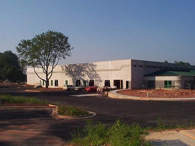 A large white building with a green roof is under construction