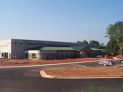 A large white building with a green roof is being built.