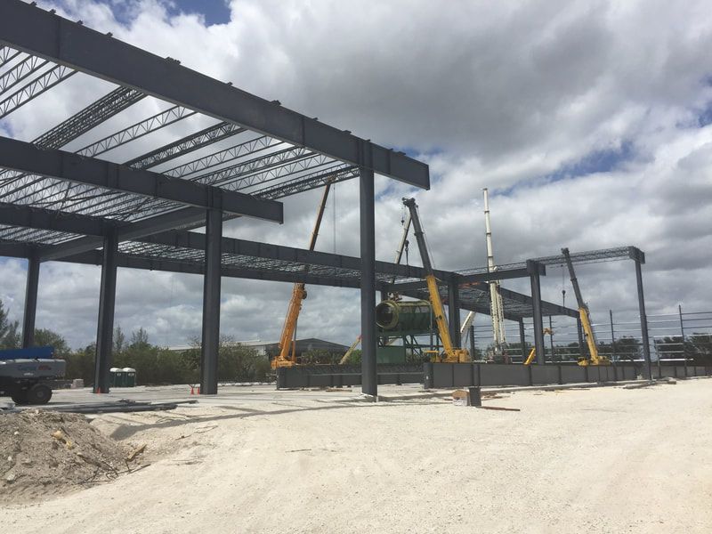 A large metal structure is being built in a dirt field.
