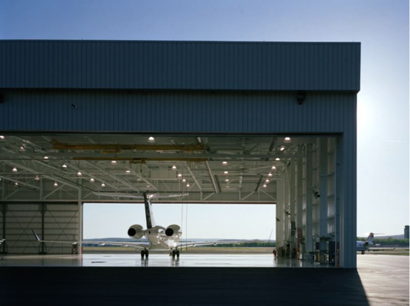 A plane is parked in a hangar with the door open.