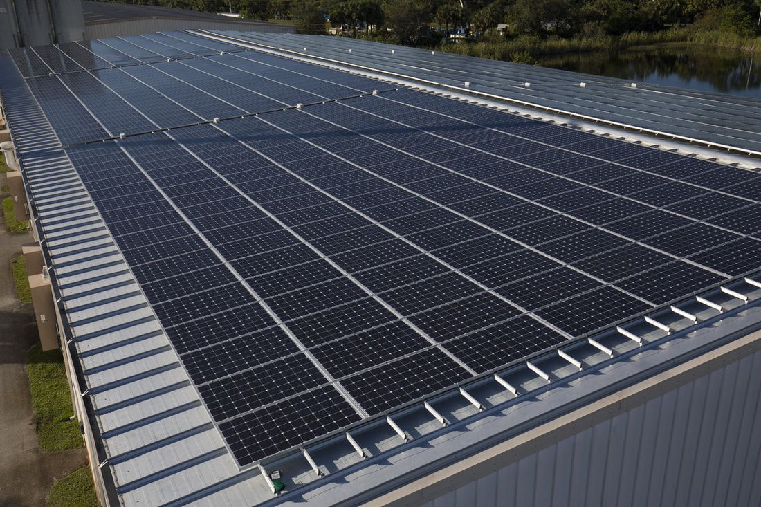 There are a lot of solar panels on the roof of a building.