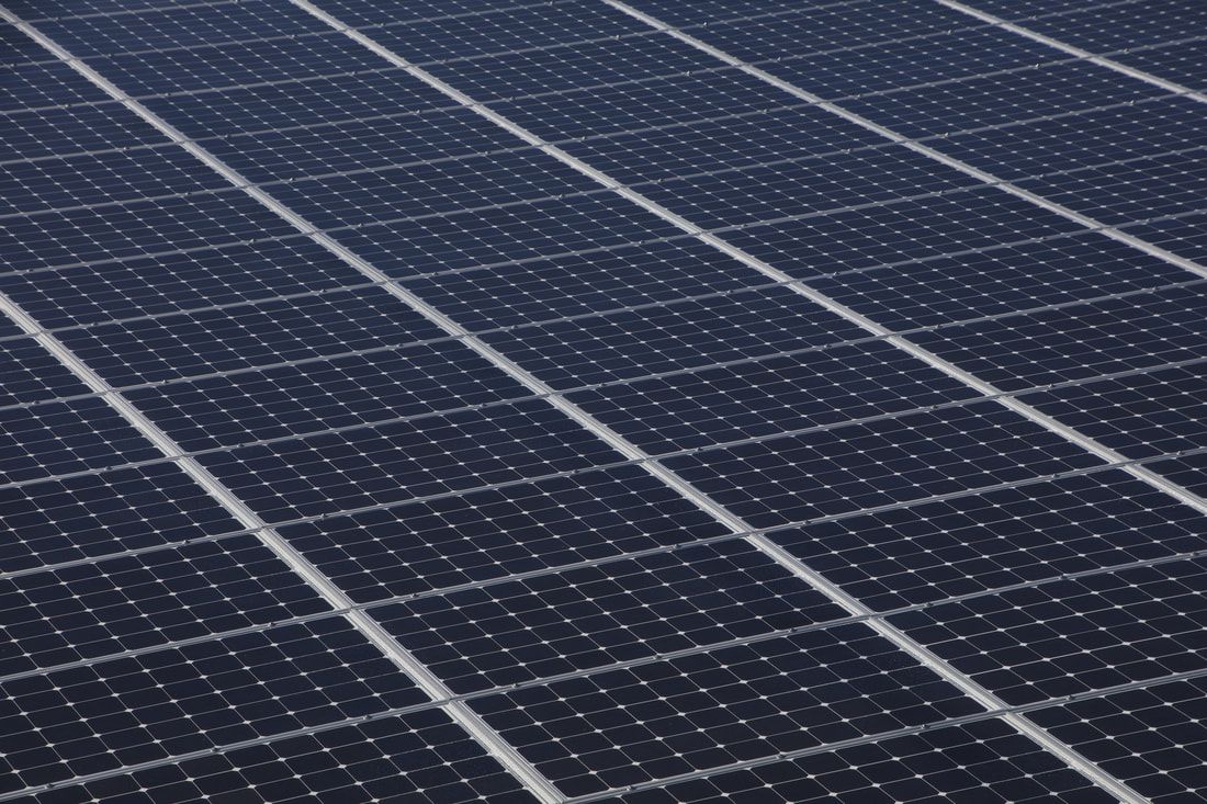 A bunch of solar panels are lined up on the ground