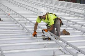 A construction worker is working on the roof of a building.