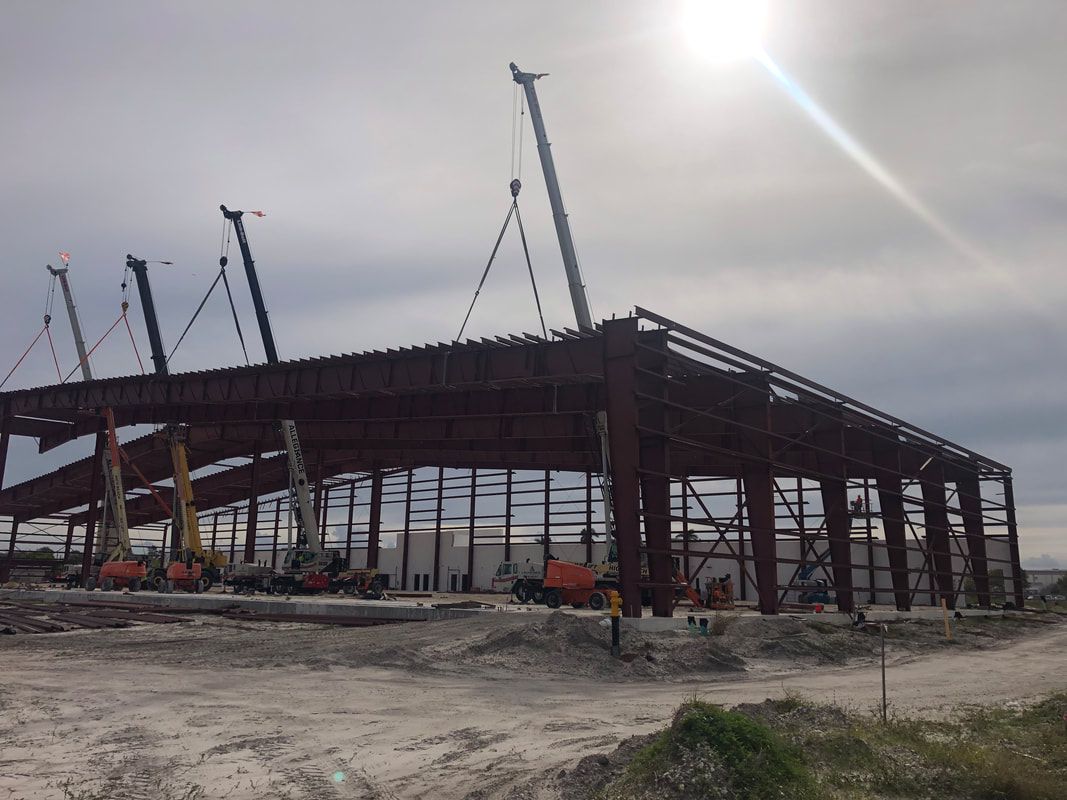 A large building is being built in the middle of a dirt field.