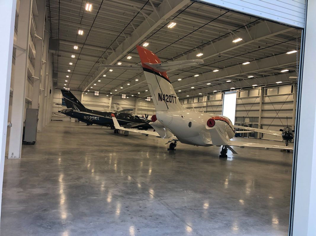 A plane is parked in a hangar with the door open.