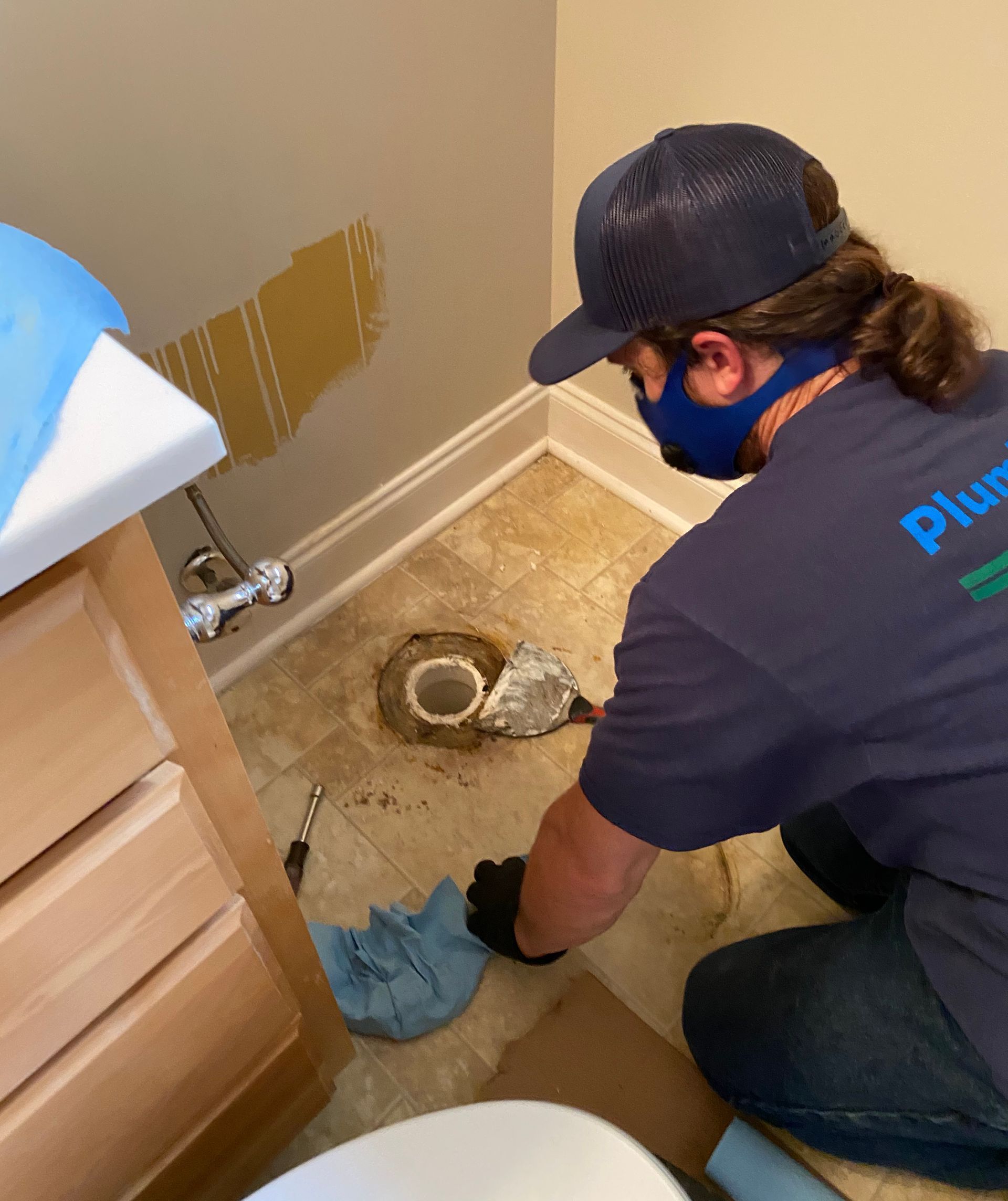 A man is fixing a toilet in a bathroom.