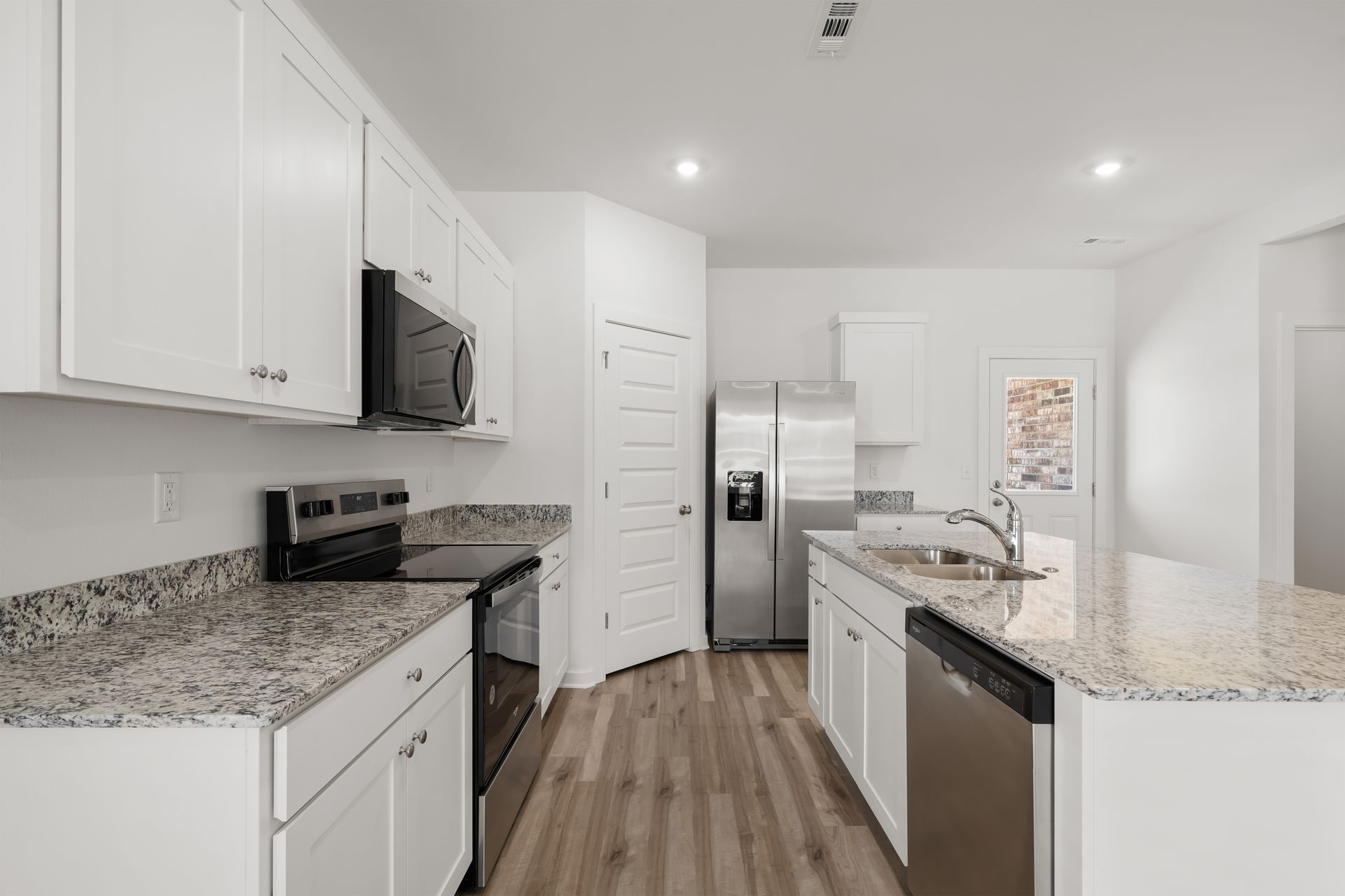 Open kitchen with white cabinetry and granite countertops