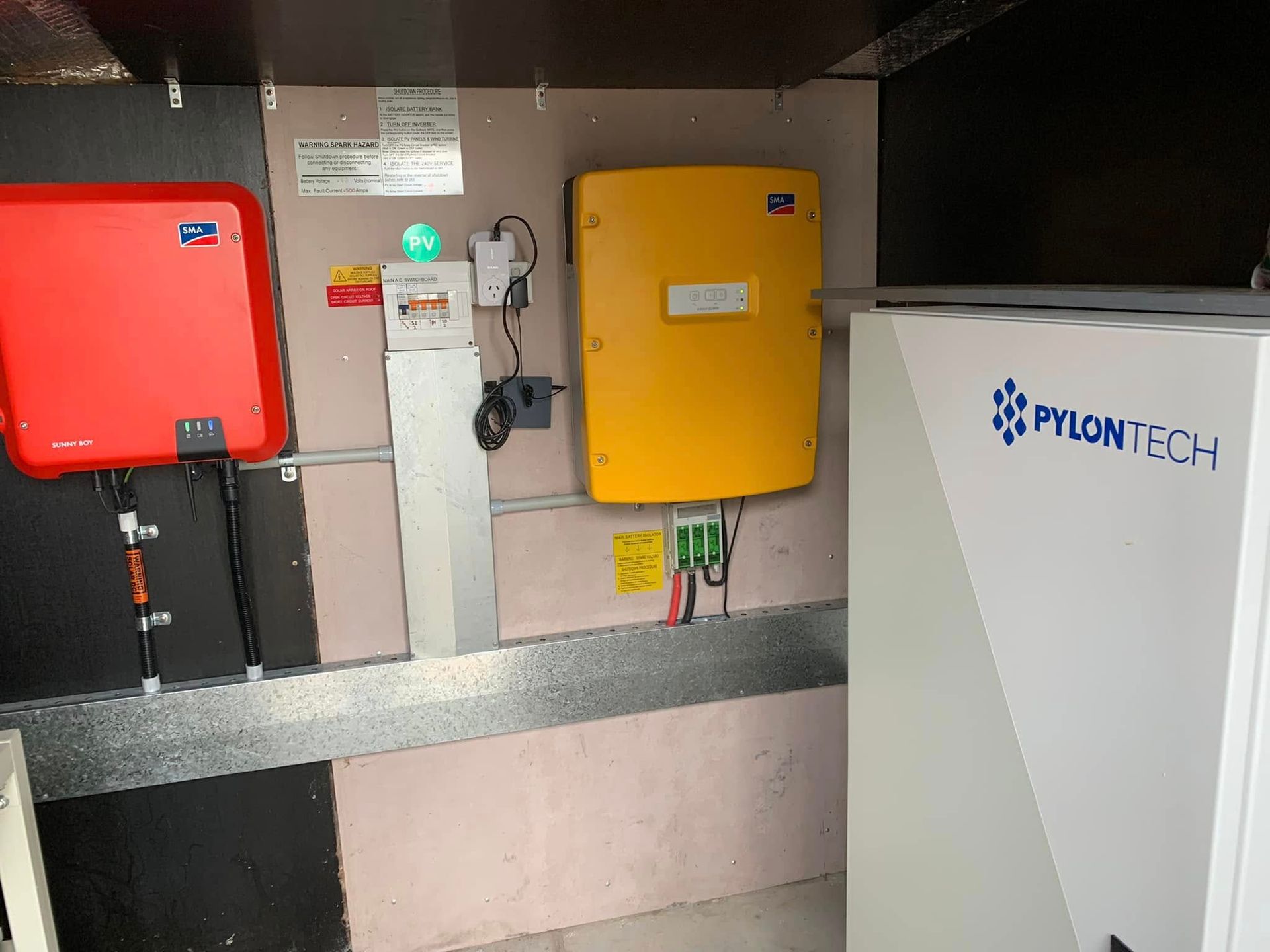 Wall-mounted electrical equipment with red and yellow boxes beside a white cabinet labeled ProlongTech