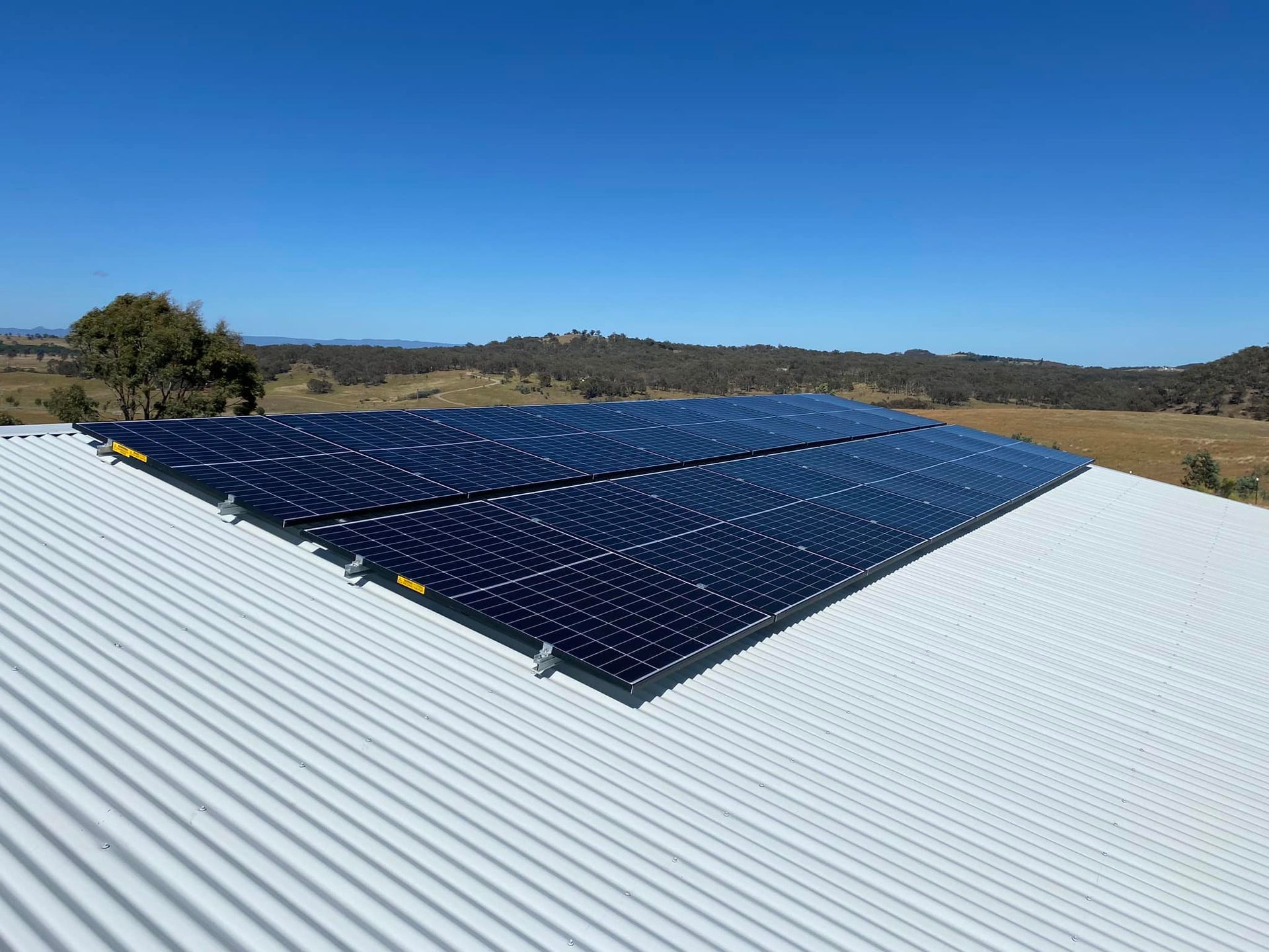 Solar panels mounted on a white roof under a clear blue sky