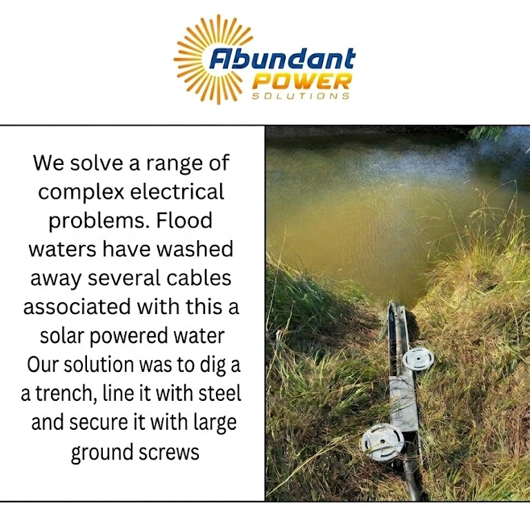 Flood-damaged solar cables secured in a trench with steel ground screws beside muddy water.