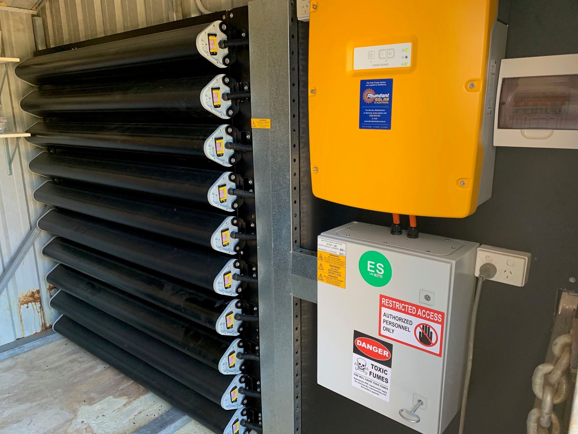 Industrial equipment with yellow and gray electrical control boxes beside black louvered vents