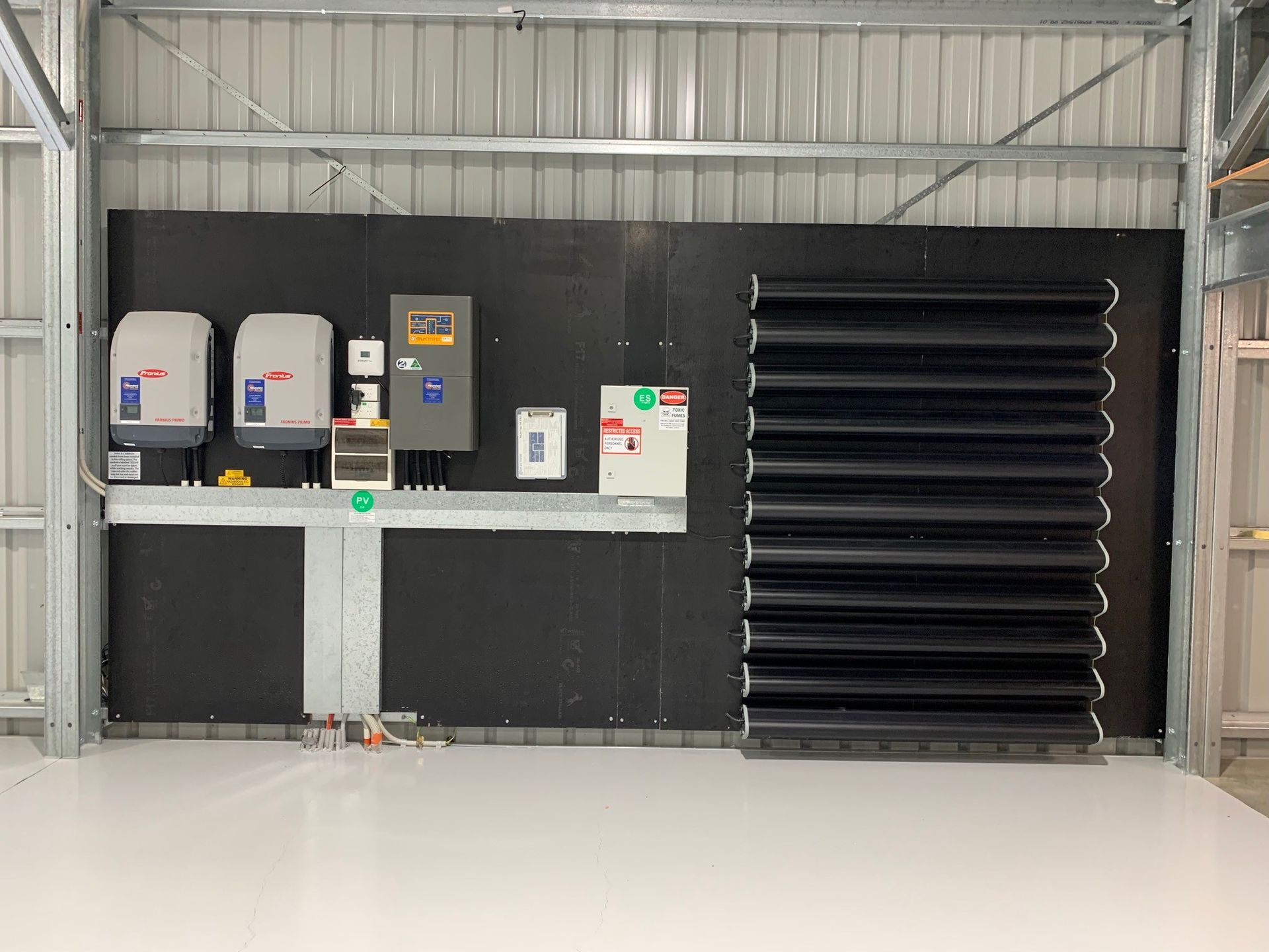 Industrial room with black equipment panels, white cabinets, and a large black vent on the right.