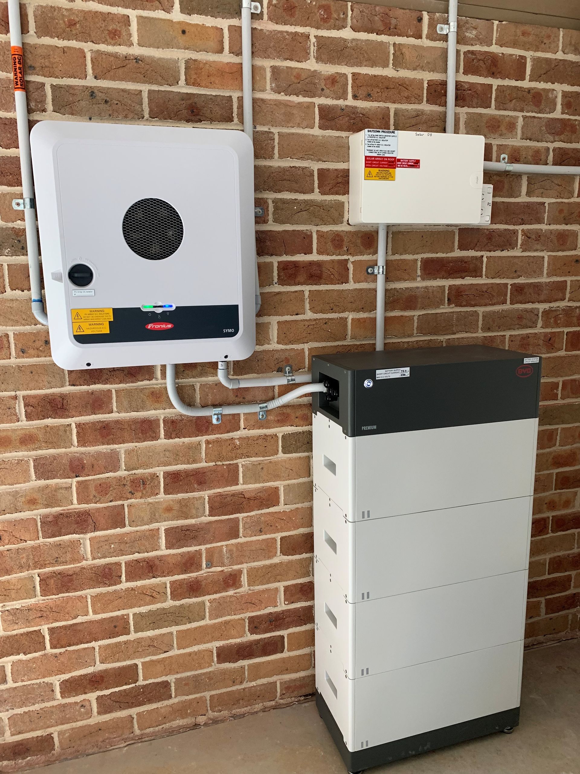 Wall-mounted electrical units and a floor battery system on a brick exterior wall