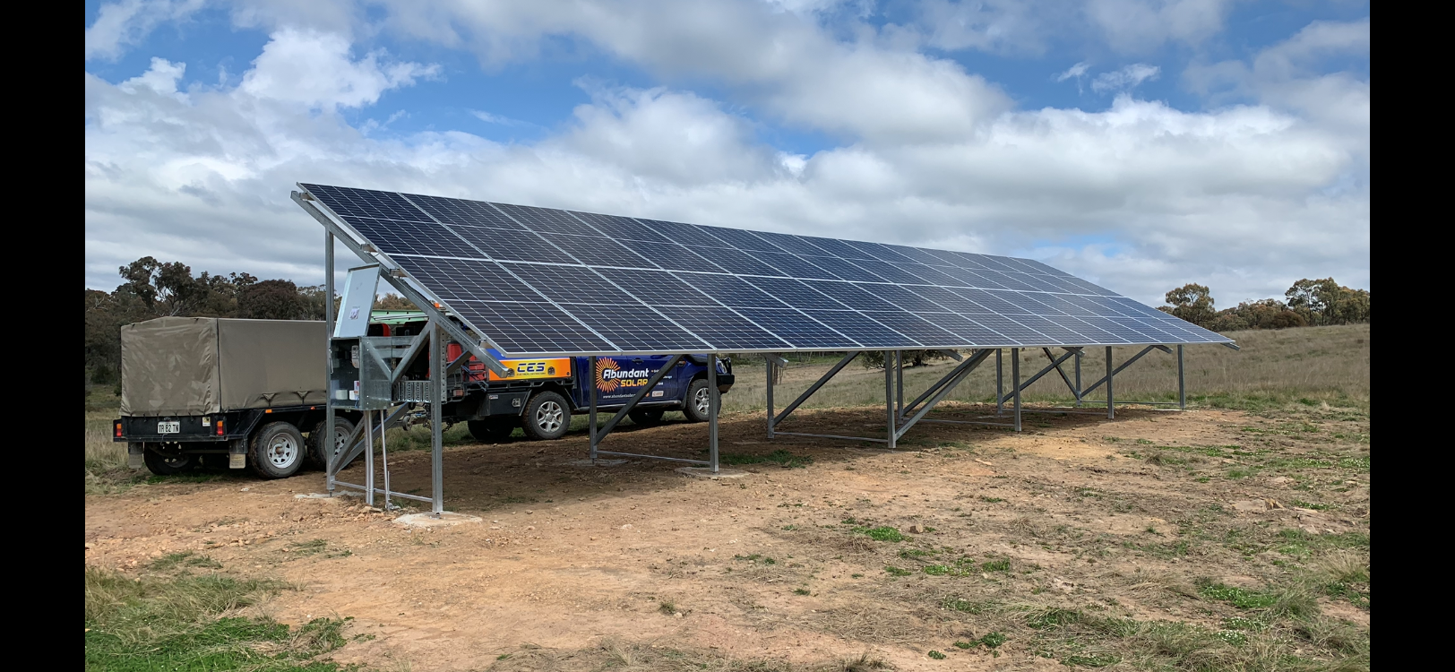Solar panel canopy over parked vehicles in a rural field
