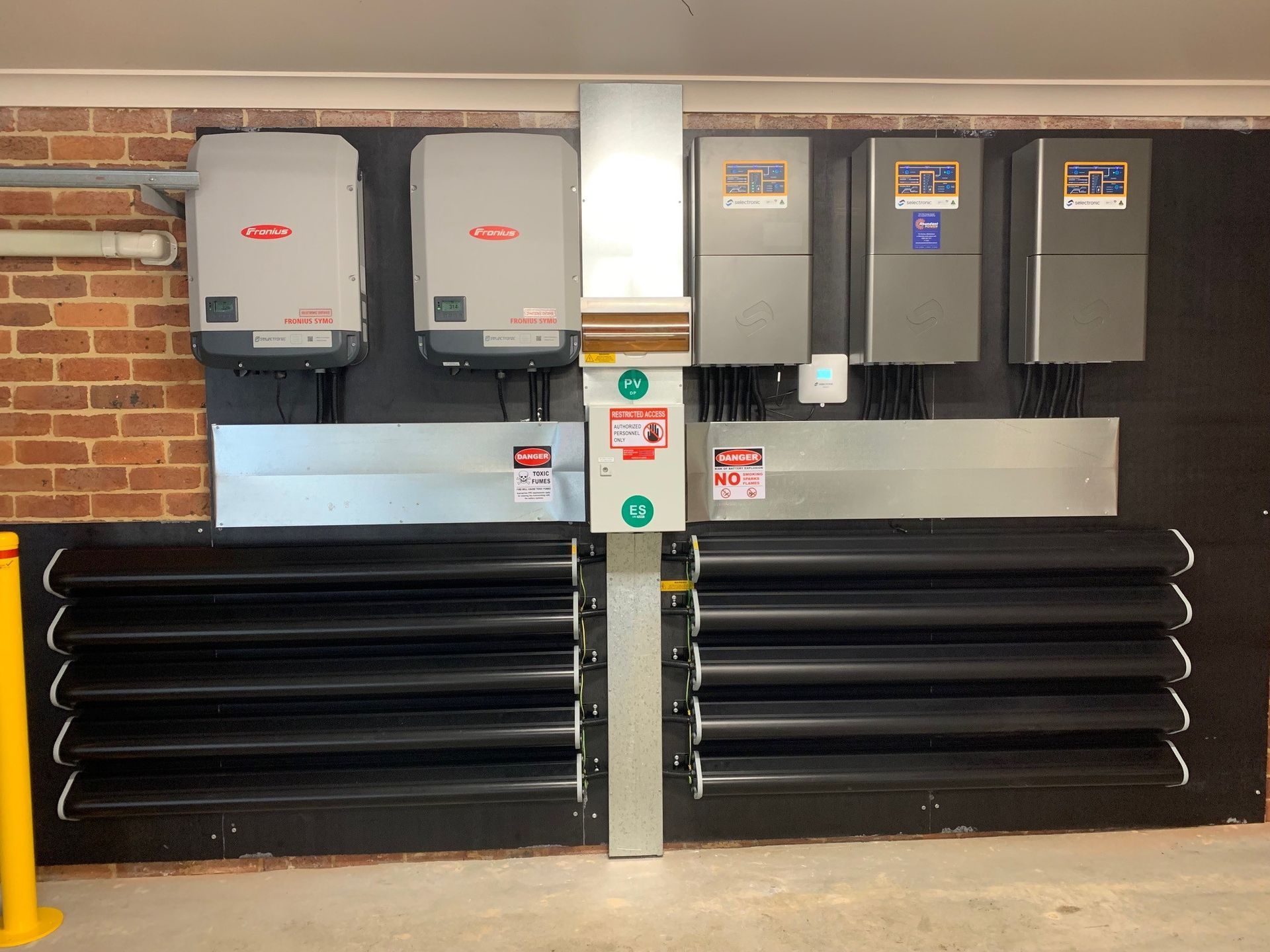 Electrical utility equipment and ventilation louvers mounted on a brick wall indoors