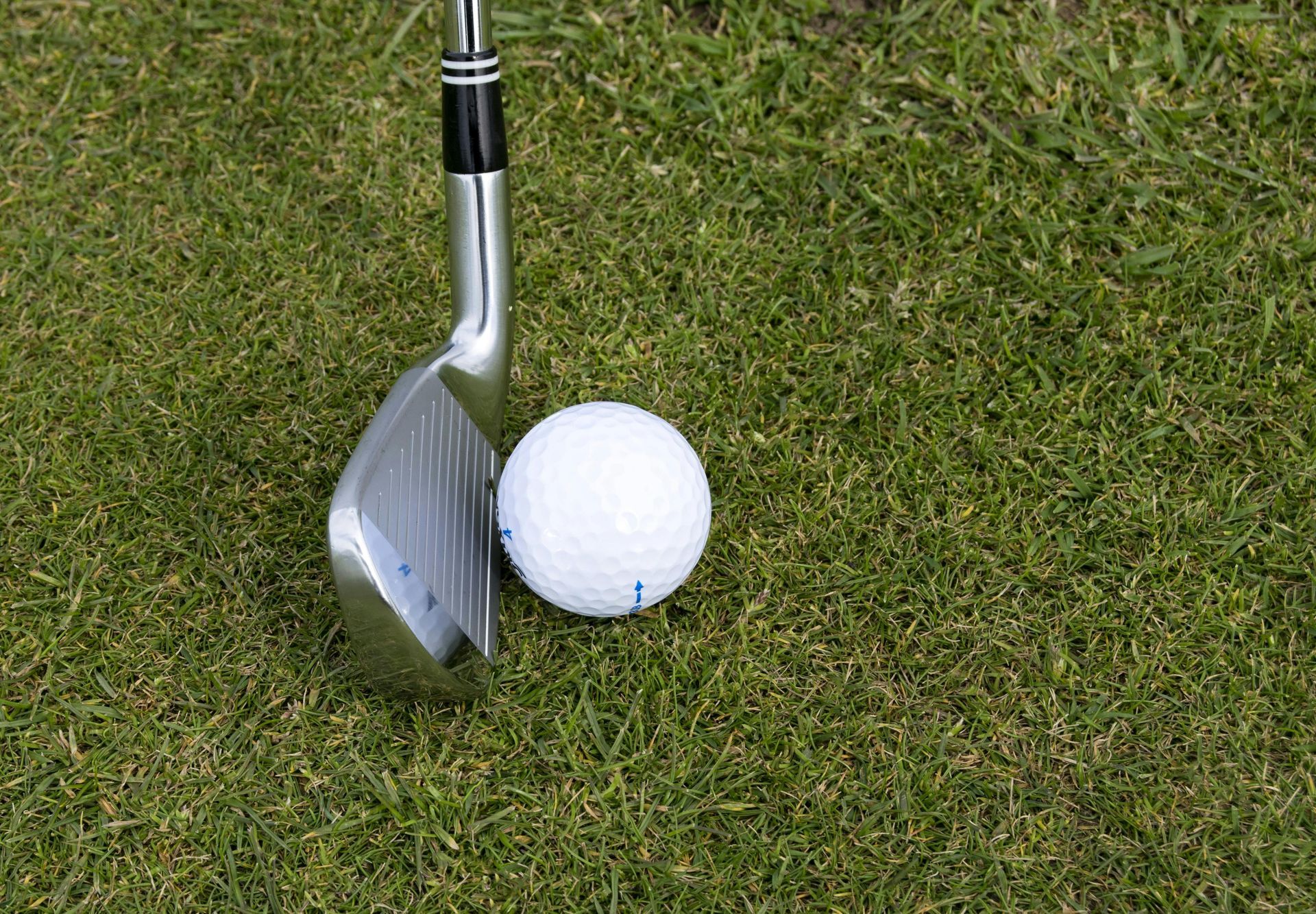 A golf club about to hit a golf ball.