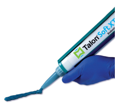 Mano guantata di blu che utilizza un applicatore Talon Soft XT per erogare gel blu su uno sfondo bianco.