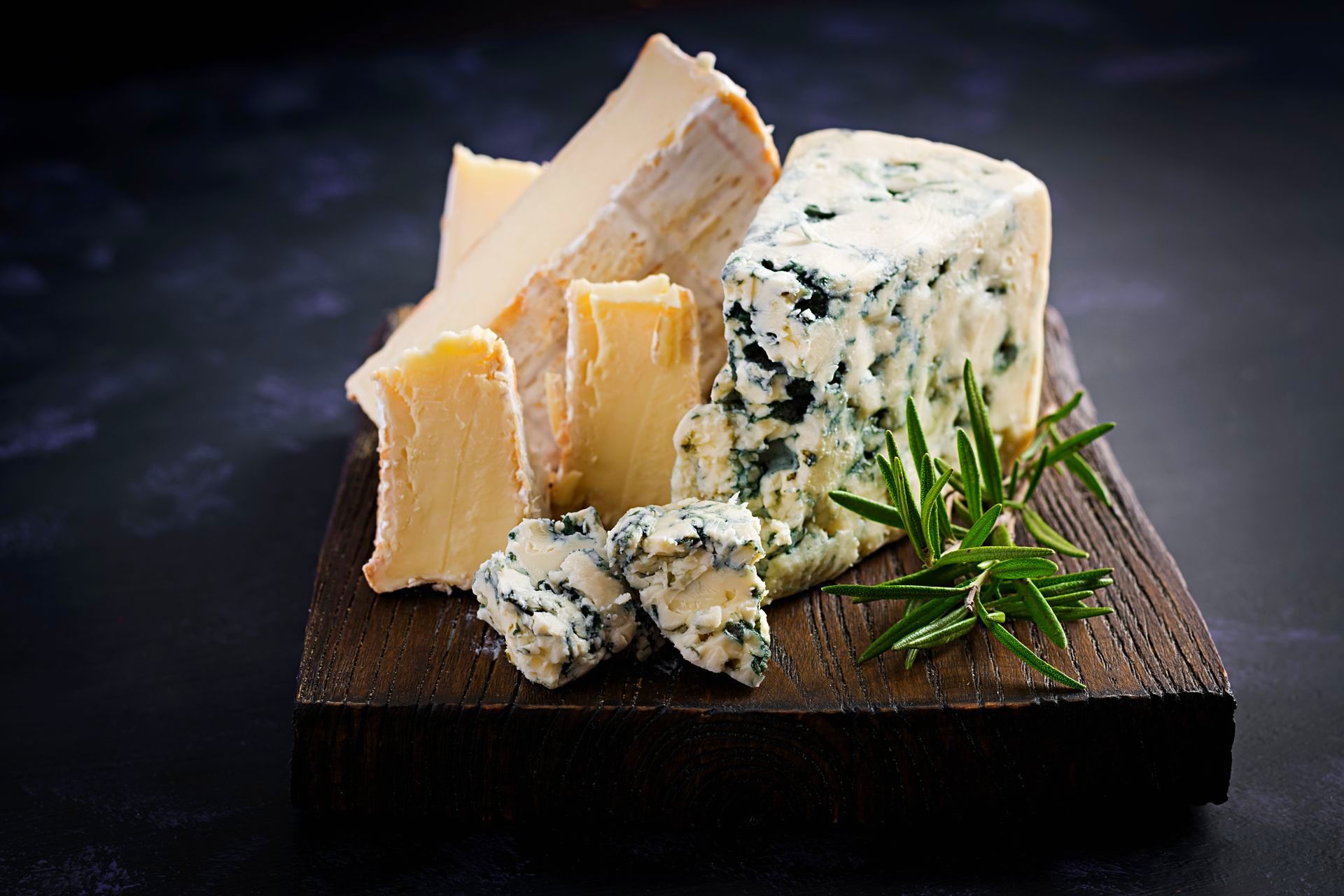 A piece of cheese is sitting on top of a wooden cutting board.