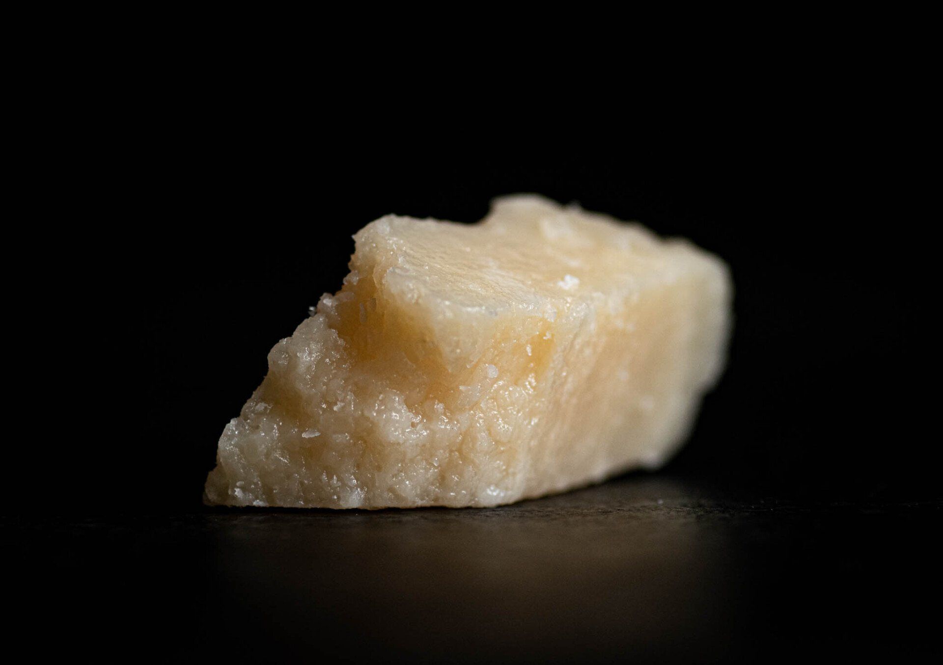 A close up of a piece of cheese on a black surface.