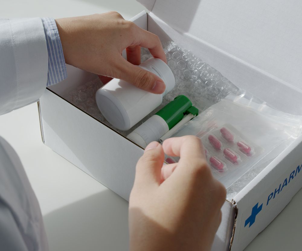 A person is putting pills in a box that says pharma