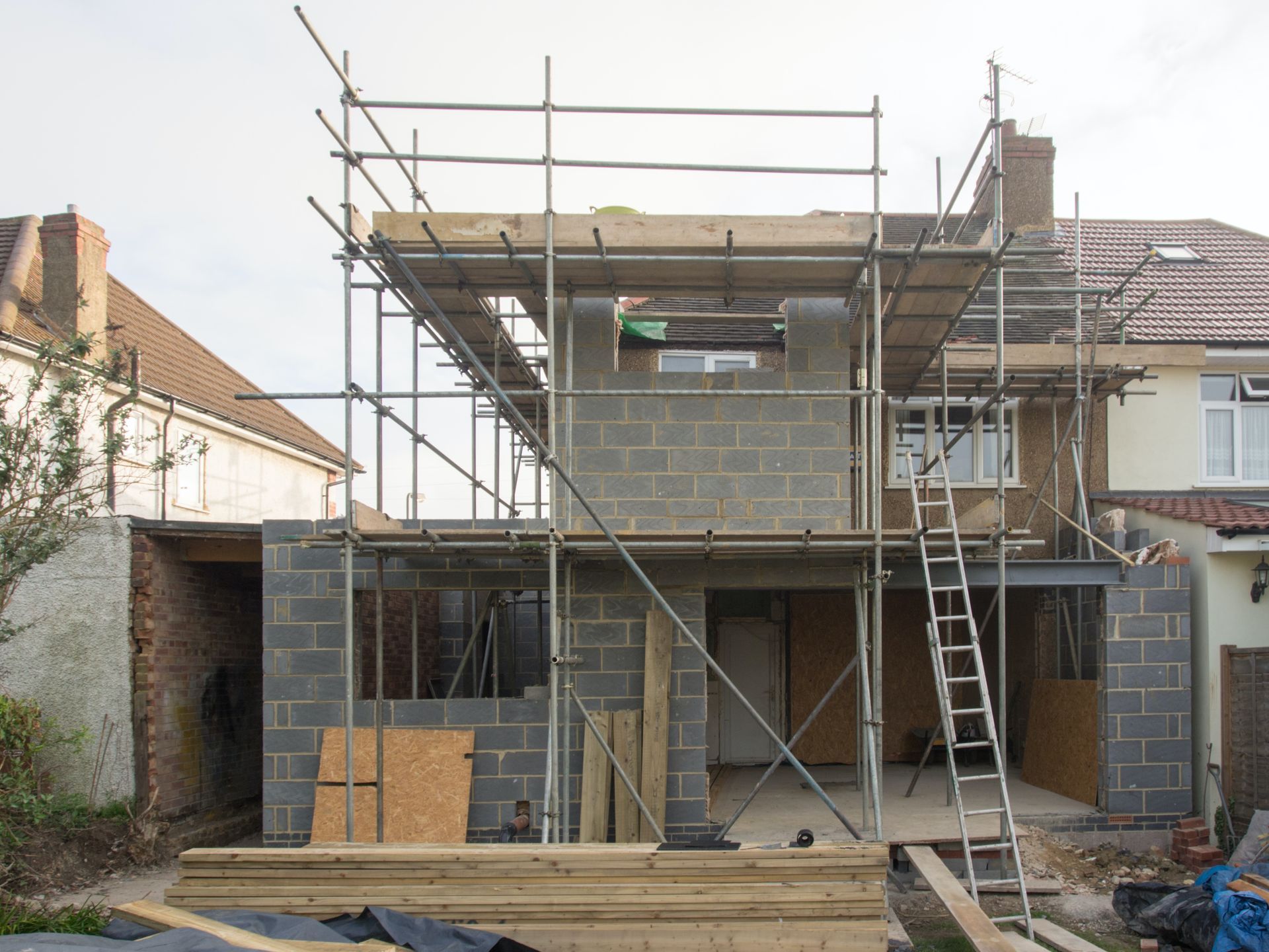 House under construction with scaffolding and cinder block walls.