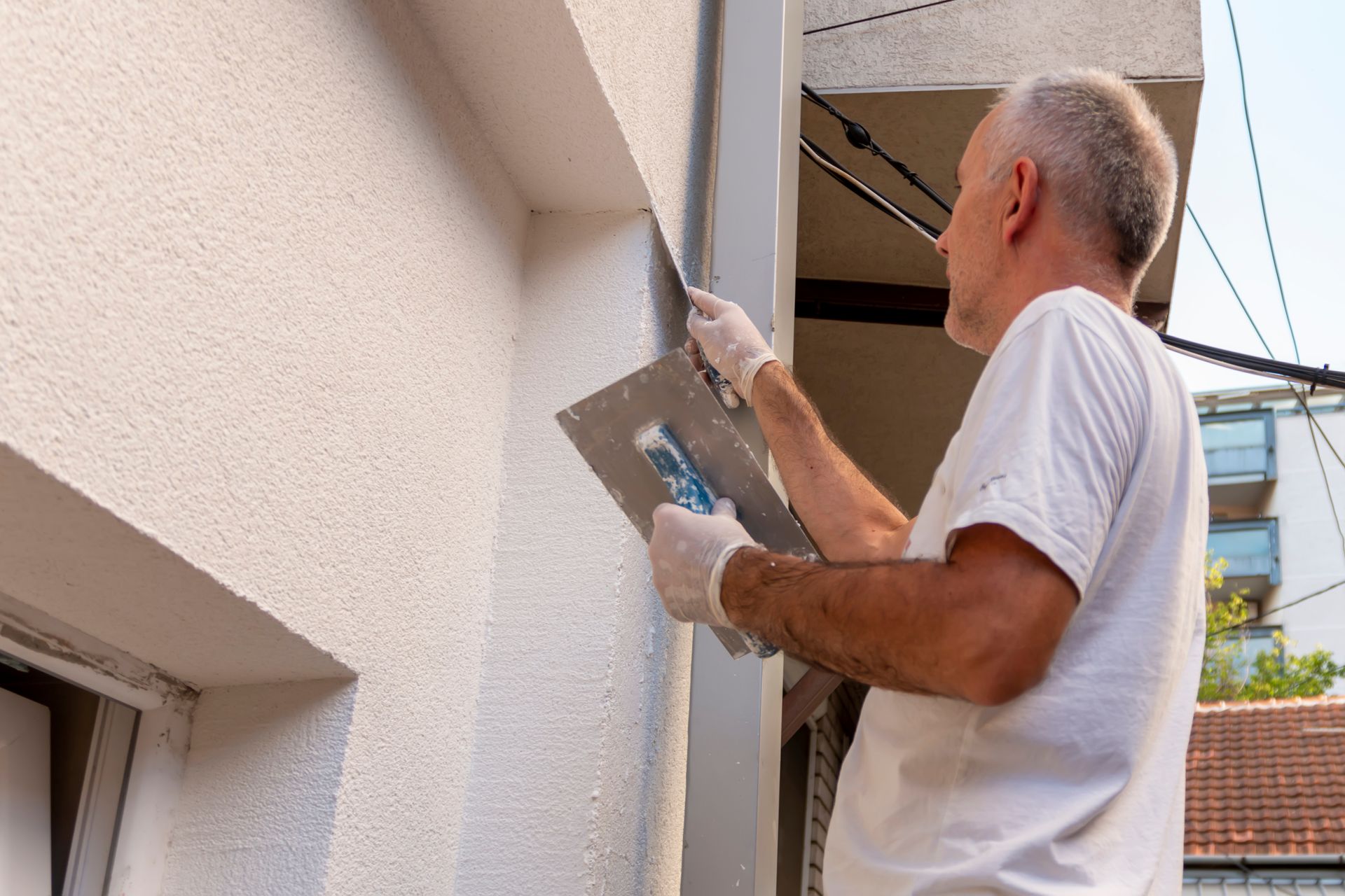 A man is plastering a wall with a trowel.