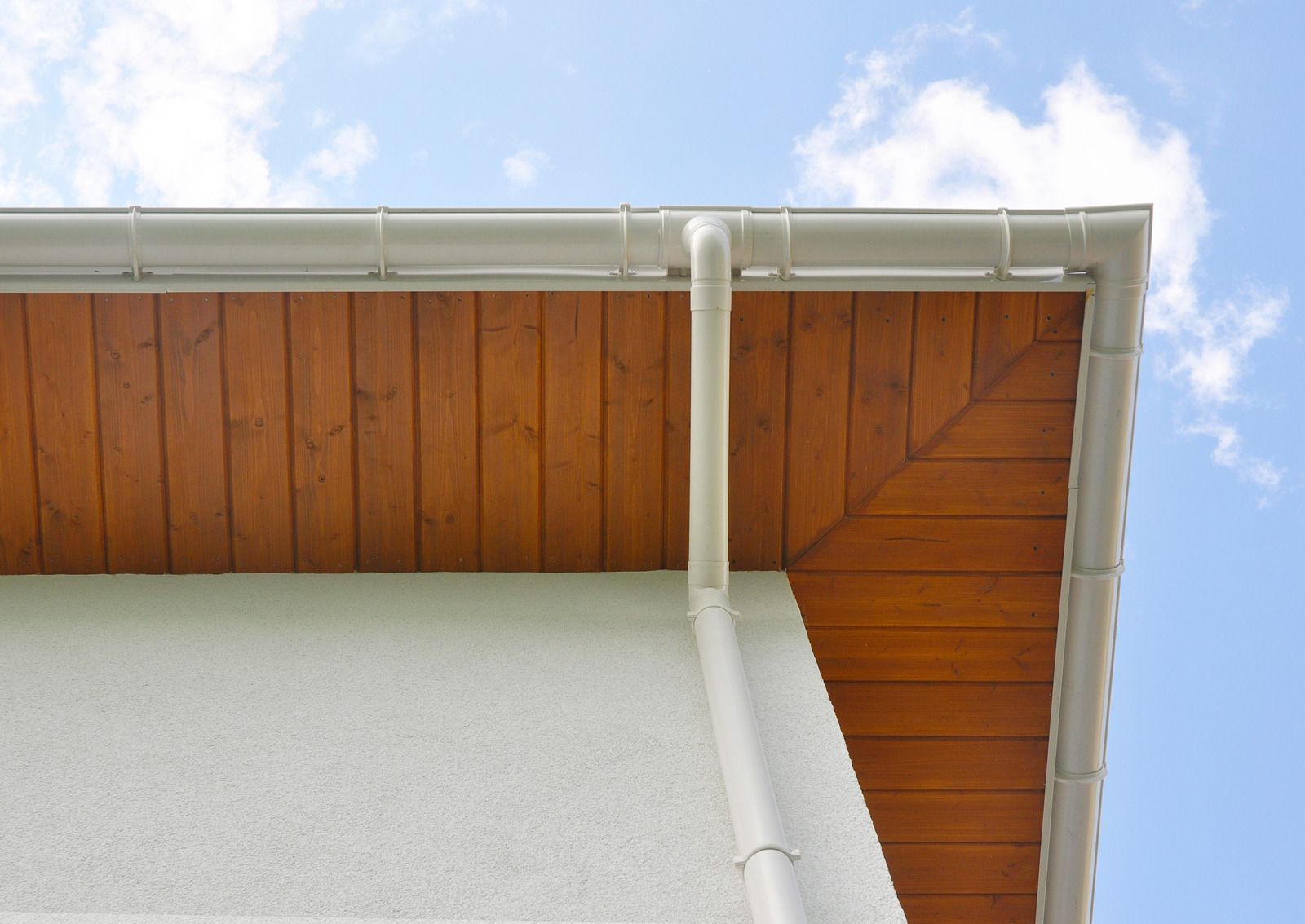 Exterior corner of a gray apartment building with stone and siding, seen from below