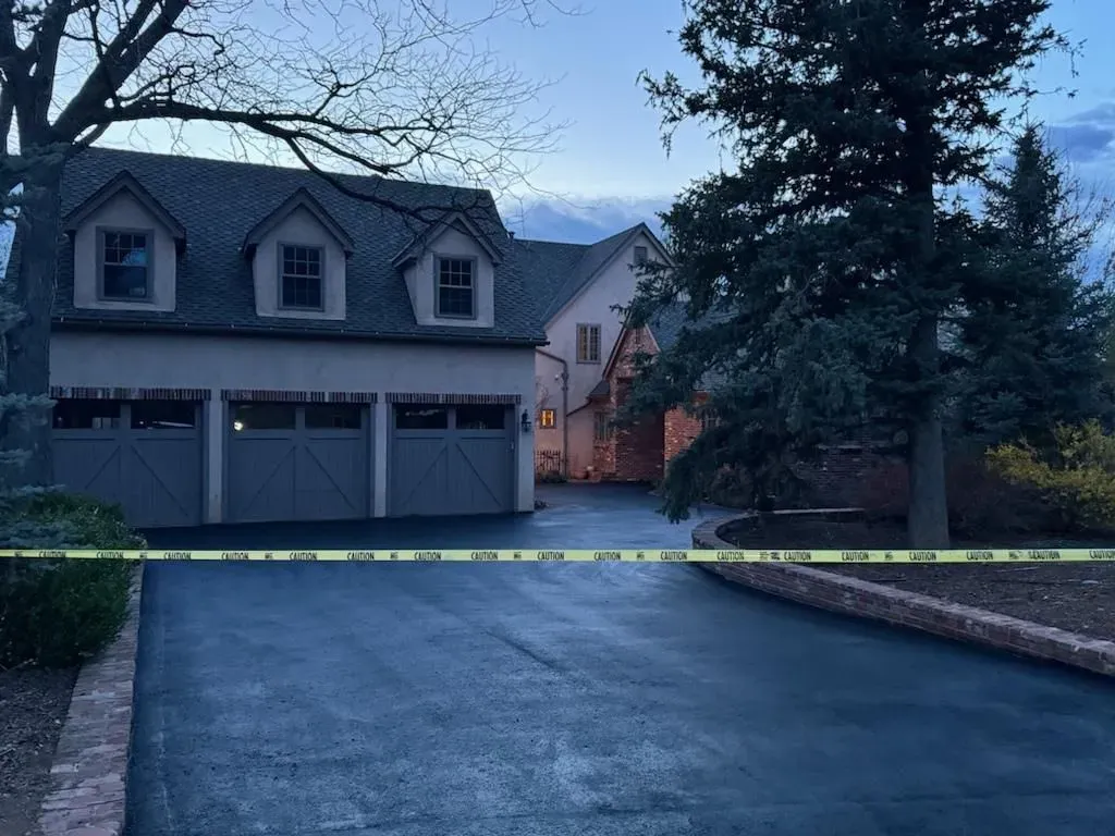 A house with a garage and a driveway surrounded by tape