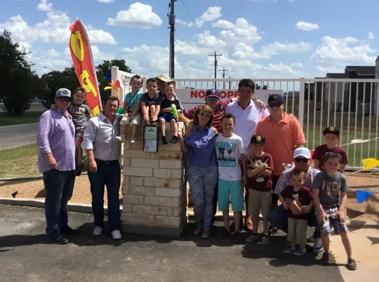 a group of people are posing for a picture in front of a brick wall .