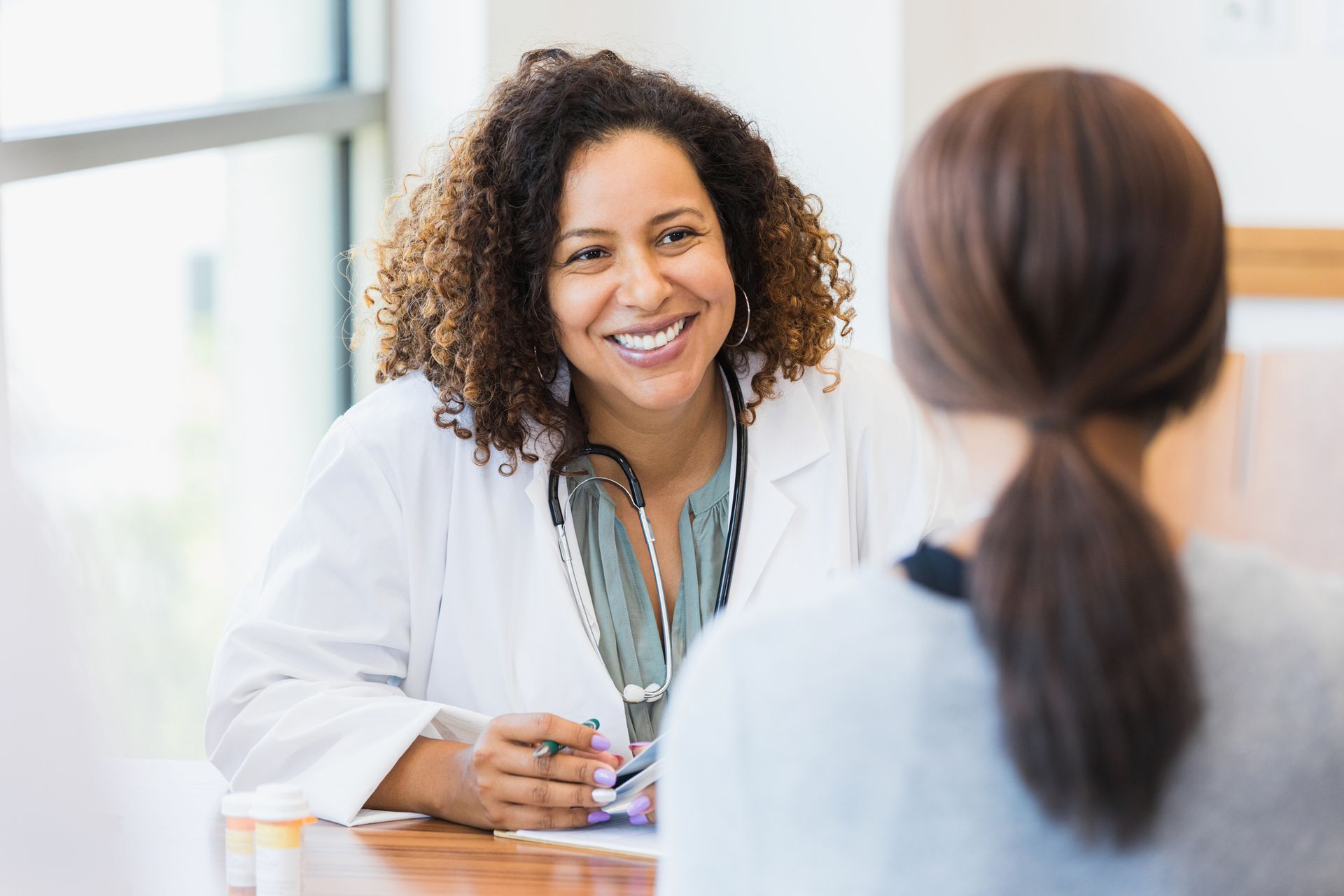 A female doctor is smiling while talking to a patient.