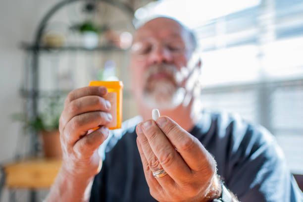 A man is holding a bottle of pills and a pill in his hand.