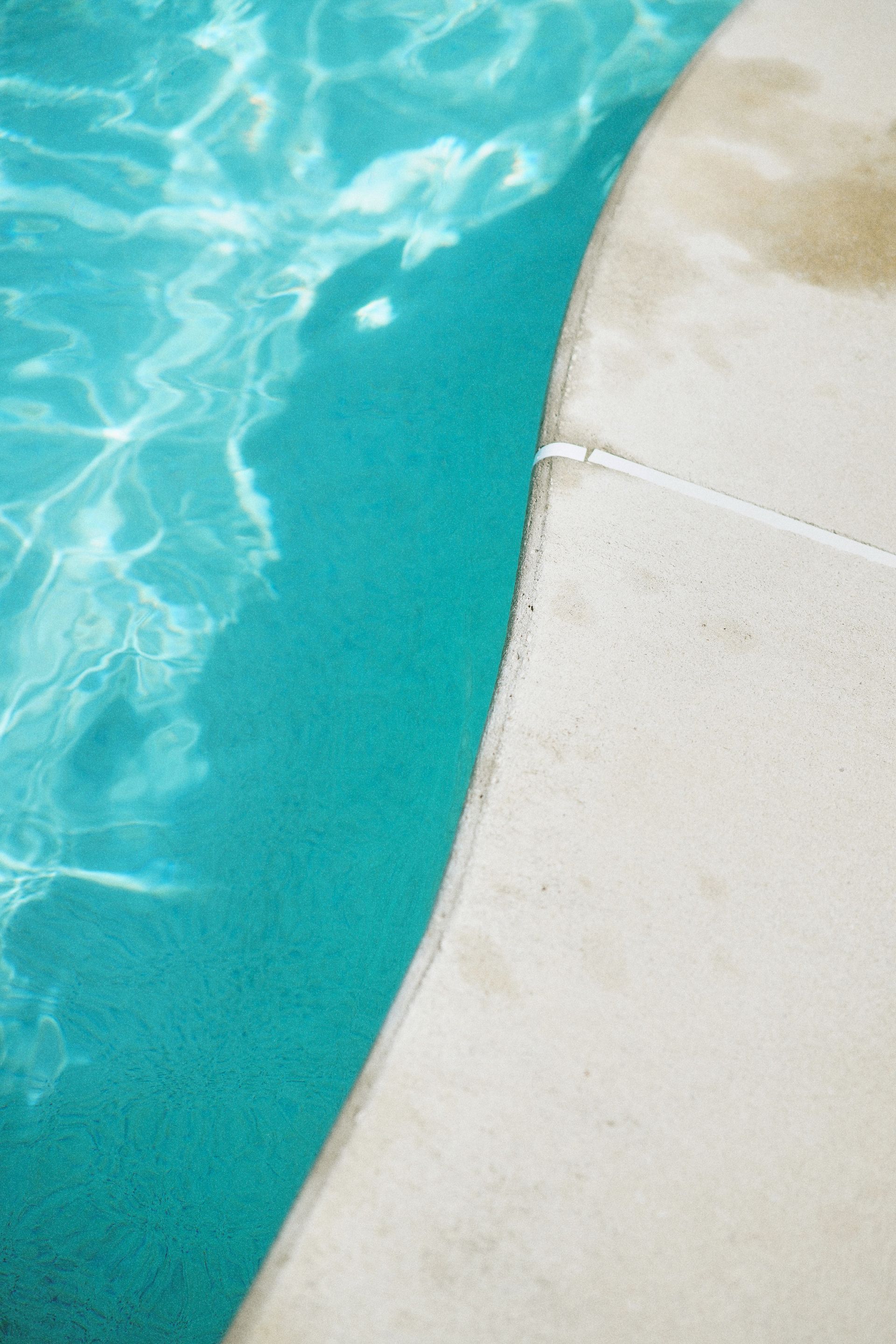 Turquoise swimming pool water beside a curved white pool edge
