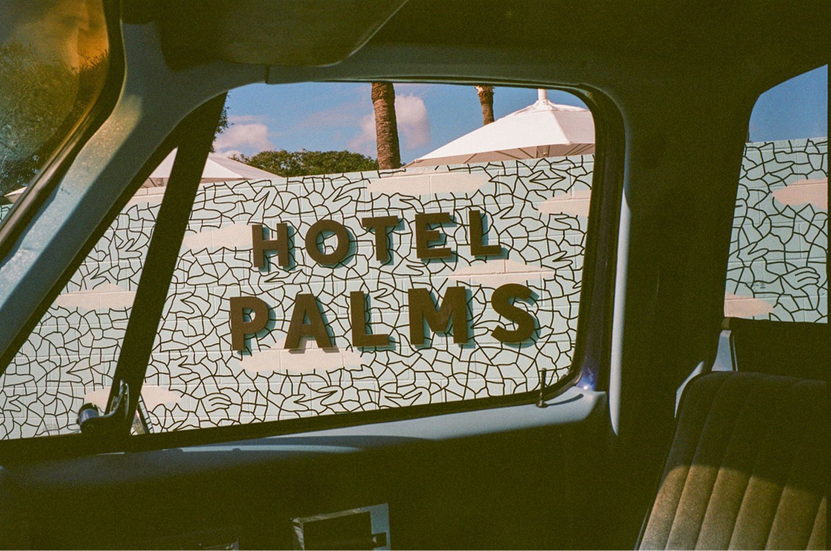 Hotel Palms sign seen through a car window at sunset