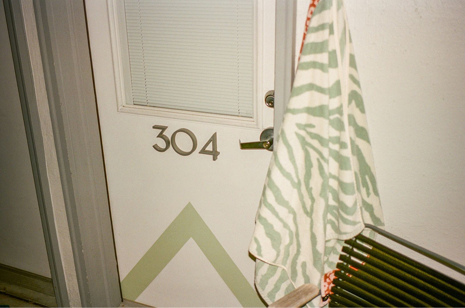 Door marked “304” with a hanging striped towel and a bench nearby