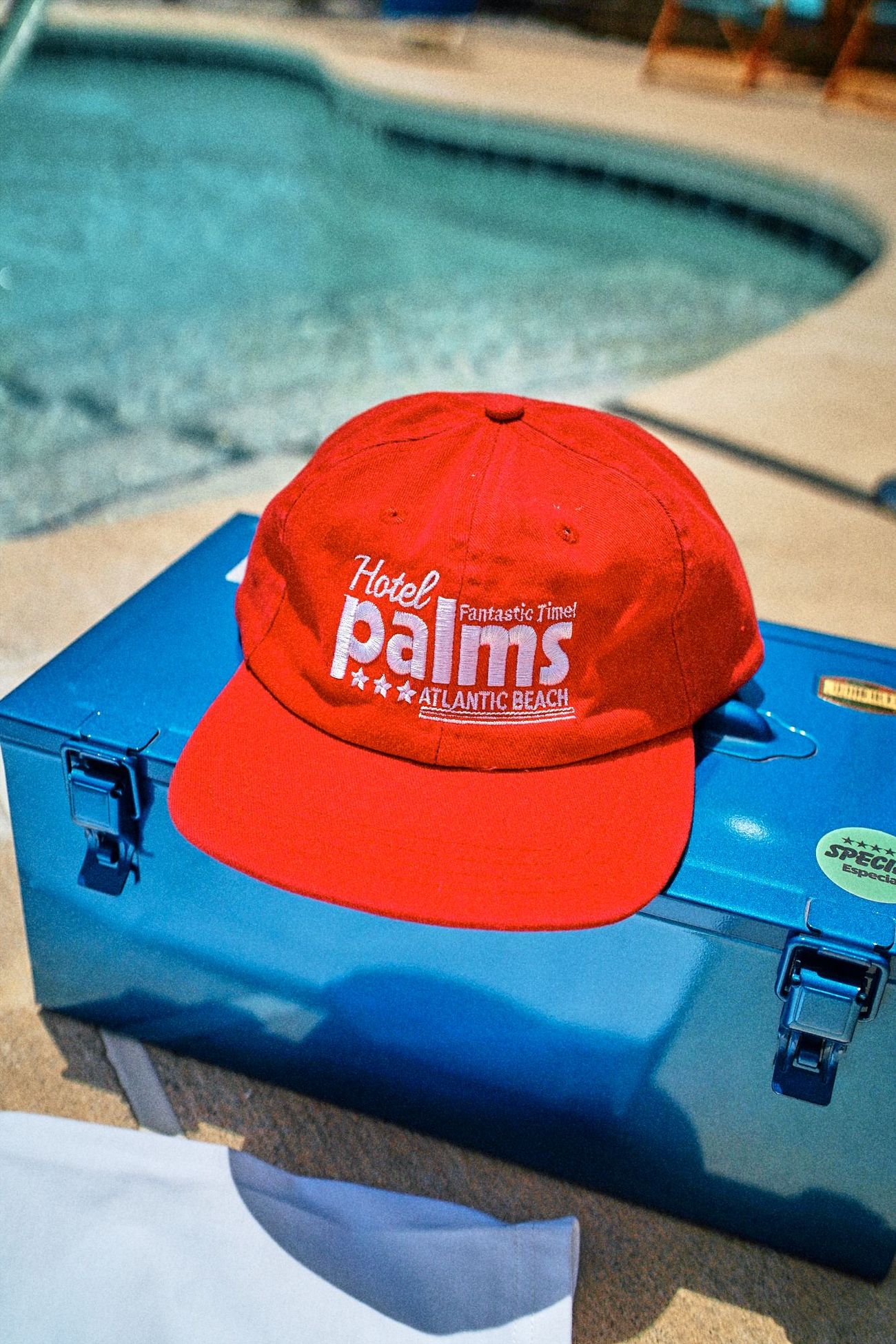 Red cap on a blue cooler beside a pool
