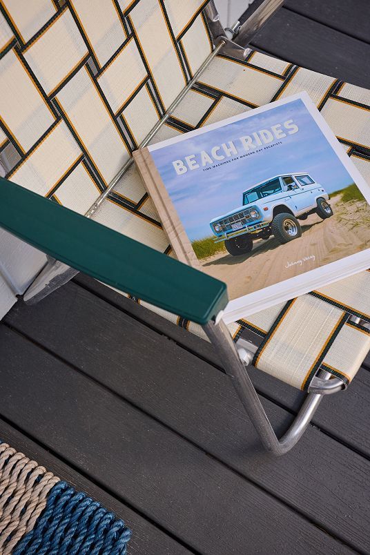 BeachHouses magazine on an outdoor chair beside a poolside deck chair.