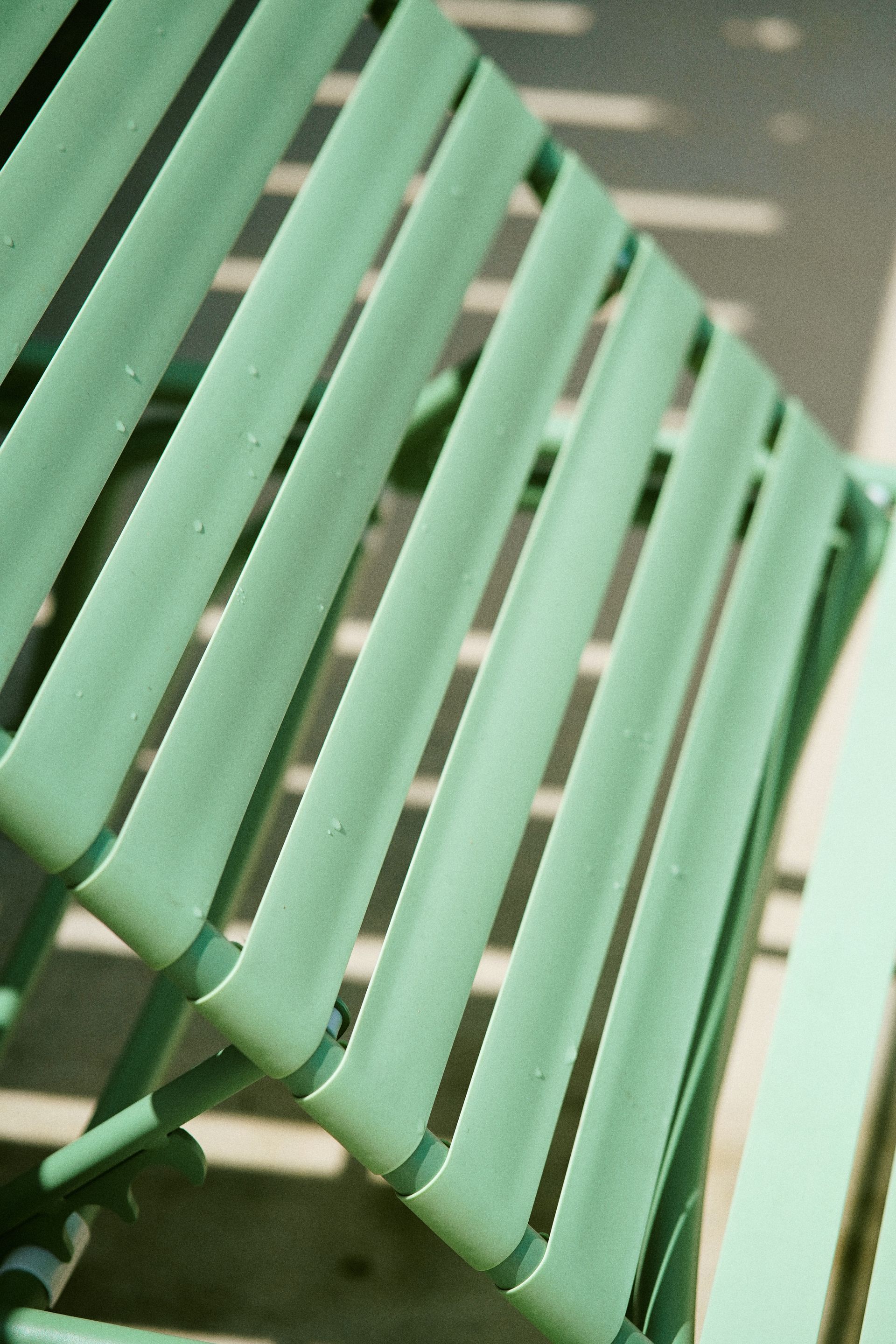 Mint-green metal slatted bench viewed at an angle indoors